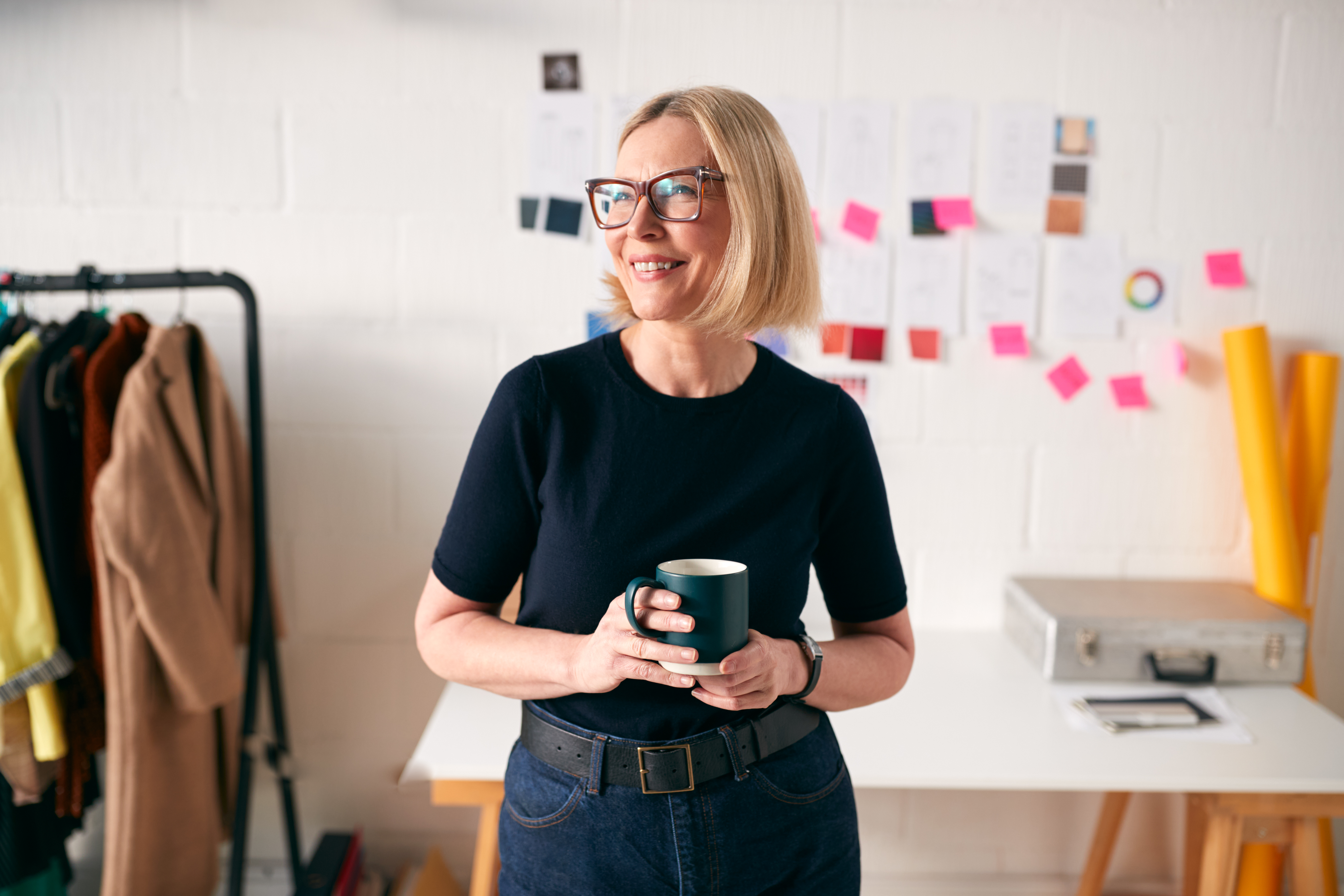 Woman with glasses smiling in front of sticky notes