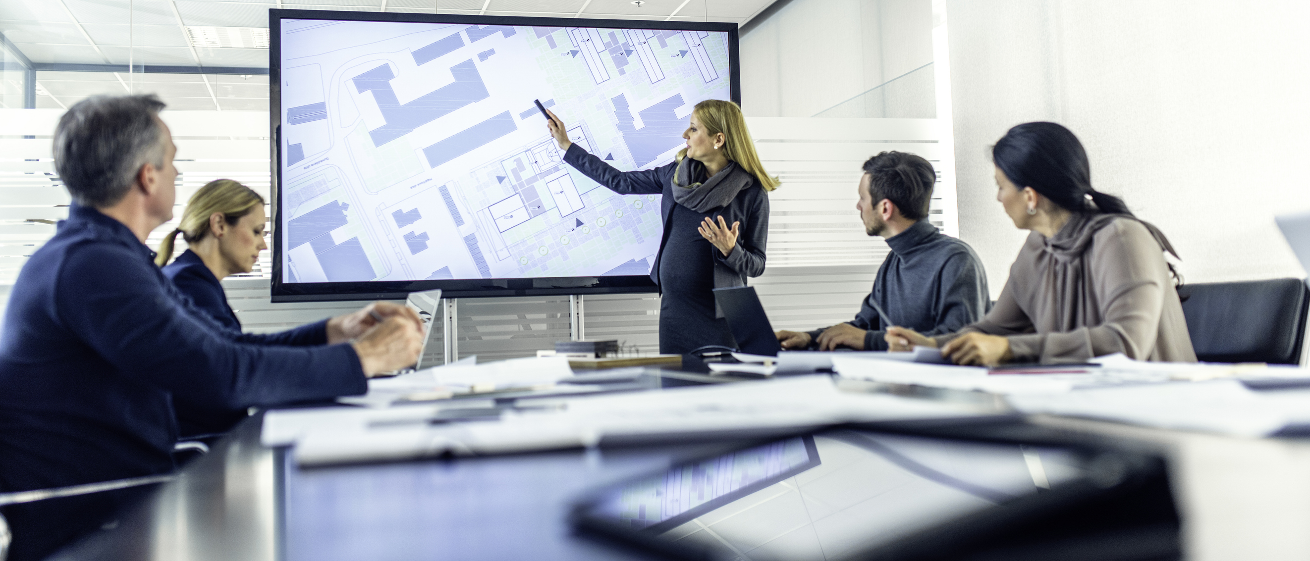 Pregnancy employee gives a presentation to three of her peers