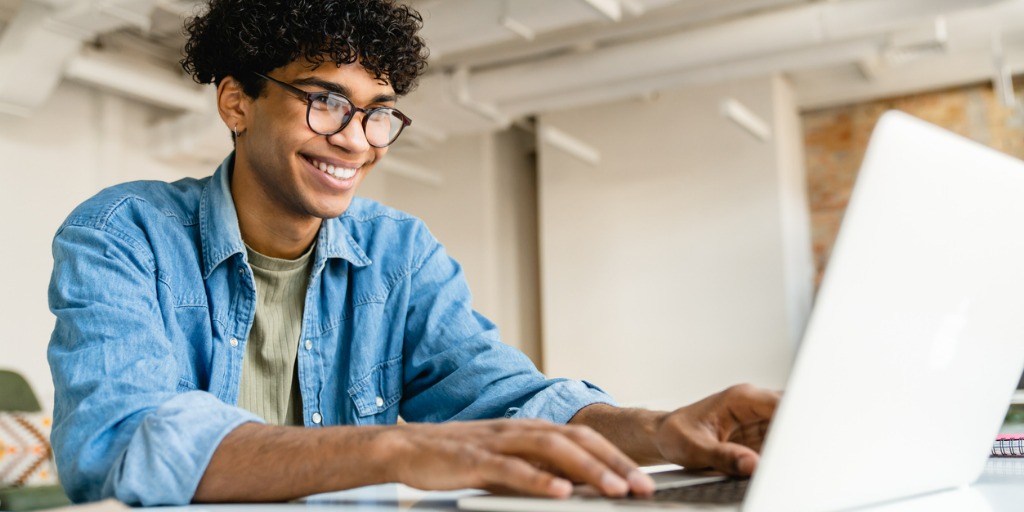 person sitting at a desk smiling and typing on a computer
