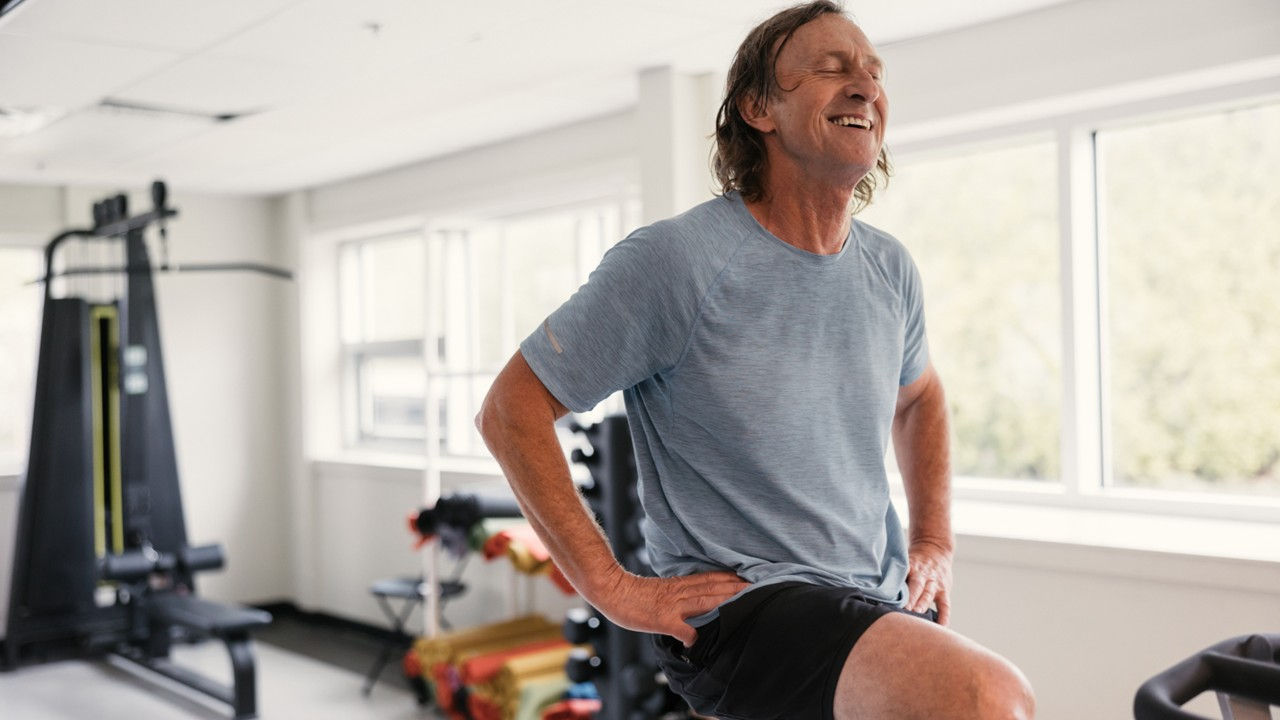 A smiling man exercising in a home gym