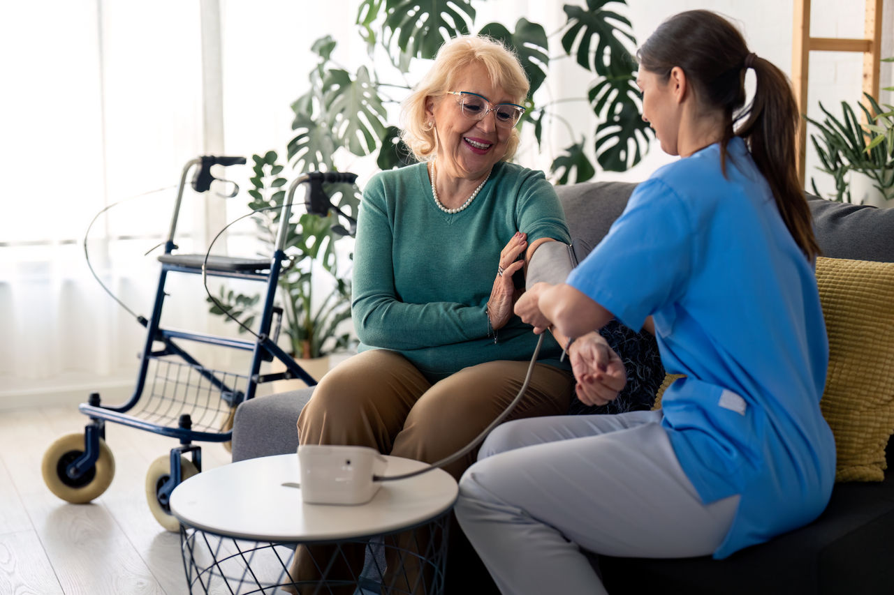 Nurse taking a patient's blood pressure in her home