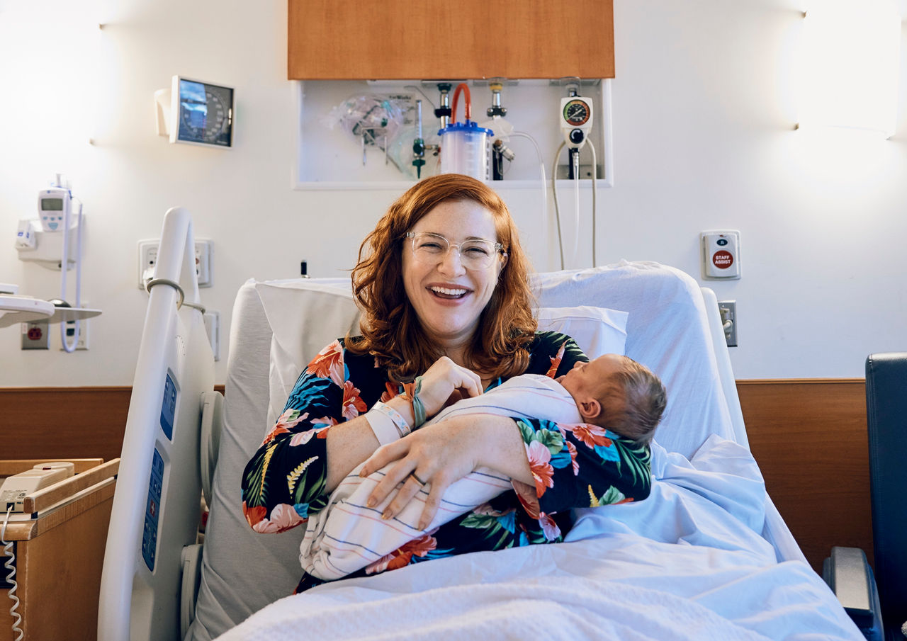Woman holding baby in hospital bed